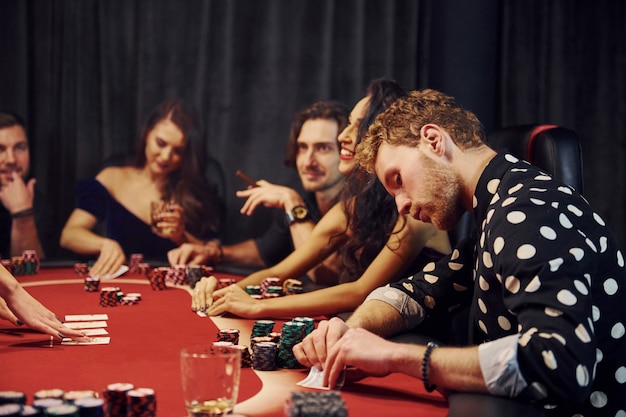 Grupo de jovens elegantes que jogando pôquer no cassino juntos