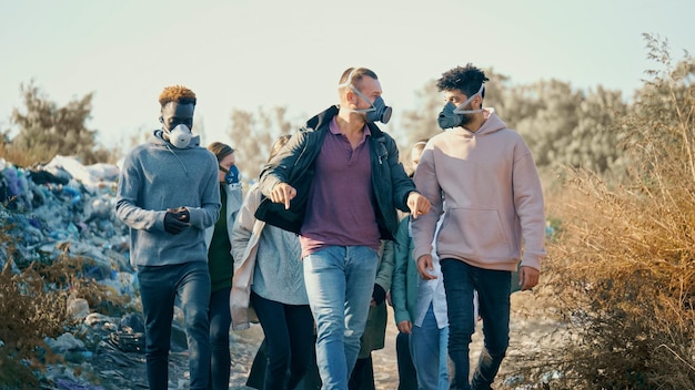 Grupo de jovens em máscaras de gás passando pela fumaça tóxica em um depósito de lixo. As pessoas se preocupam com a ecologia. Jovens ativistas em ação contra a poluição ficam em um aterro sanitário. Salvando o Planeta.