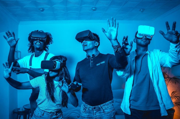 Grupo de jovens em óculos vr em um jogo de realidade virtual em uma luz azul espantado tocando objetos virtuais futuristas ou conceito de tecnologia científica