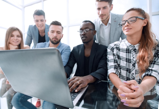 Grupo de jovens empresários confiantes analisando dados usando computador e sorrindo enquanto trabalhavam no escritório