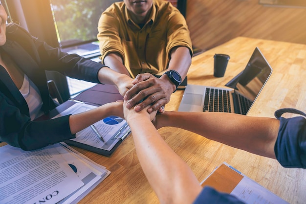 Foto grupo de jovens empresários de mãos dadas no escritório trabalho em equipe para o conceito de sucesso