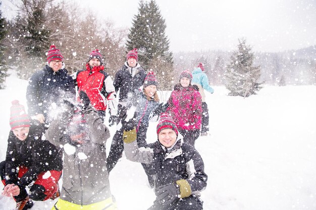 grupo de jovens empresários felizes se divertindo jogando neve no ar enquanto aproveita o dia de inverno nevado com flocos de neve ao redor deles durante uma formação de equipe na floresta de montanha