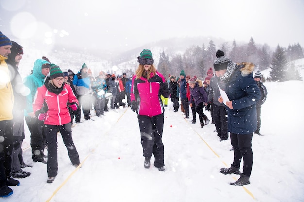 grupo de jovens empresários felizes tendo uma competição de jogos de olhos vendados enquanto aproveita o dia de inverno nevado com flocos de neve ao redor deles durante uma formação de equipe na floresta de montanha