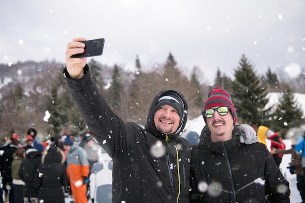 grupo de jovens empresários felizes tomando uma selfie enquanto se diverte no dia de inverno nevado com flocos de neve ao redor deles durante uma formação de equipe na floresta de montanha