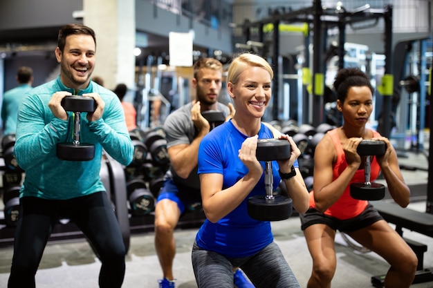 Grupo de jovens esportivos no ginásio. Treino de amigos felizes em forma, exercício no clube de fitness