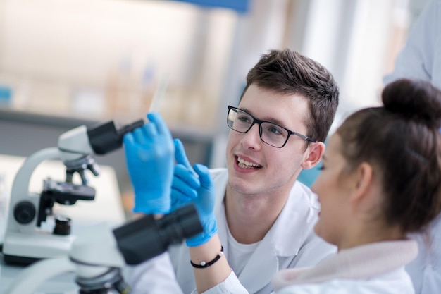 Grupo de jovens estudantes de medicina fazendo pesquisa juntos no laboratório de química, trabalho em equipe por estudante universitário dentro de casa