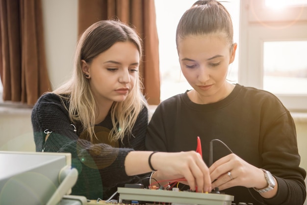 Grupo de jovens estudantes fazendo prática profissional técnica com professor na sala de aula eletrônica, conceito de educação e tecnologia