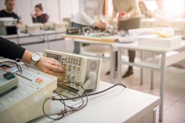 Grupo de jovens estudantes fazendo prática profissional técnica com professor na sala de aula eletrônica, conceito de educação e tecnologia