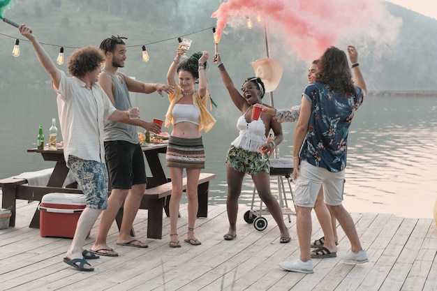 Grupo de jovens felizes em um píer e se divertindo, visitando a festa de verão