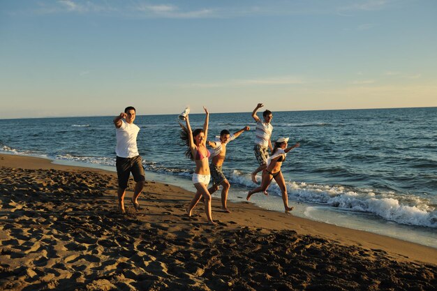 grupo de jovens felizes se divertem correndo e pulando em beacz na hora do pôr do sol