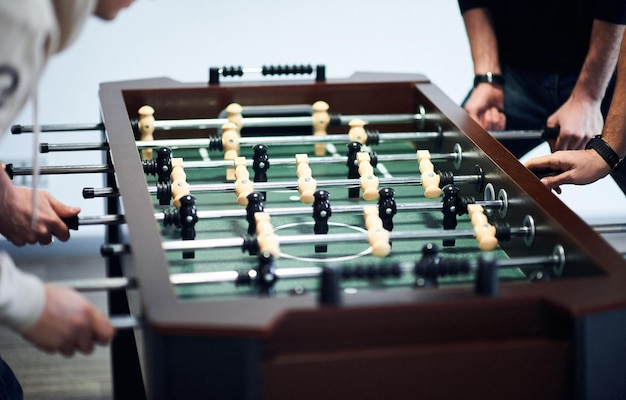 Grupo de jovens jogando futebol de mesa no escritório