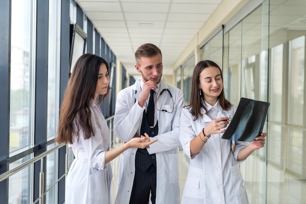 Grupo de jovens médicos discute e procura a perna de varredura de raio-x em uma clínica. Conceito de trabalho médico em equipe