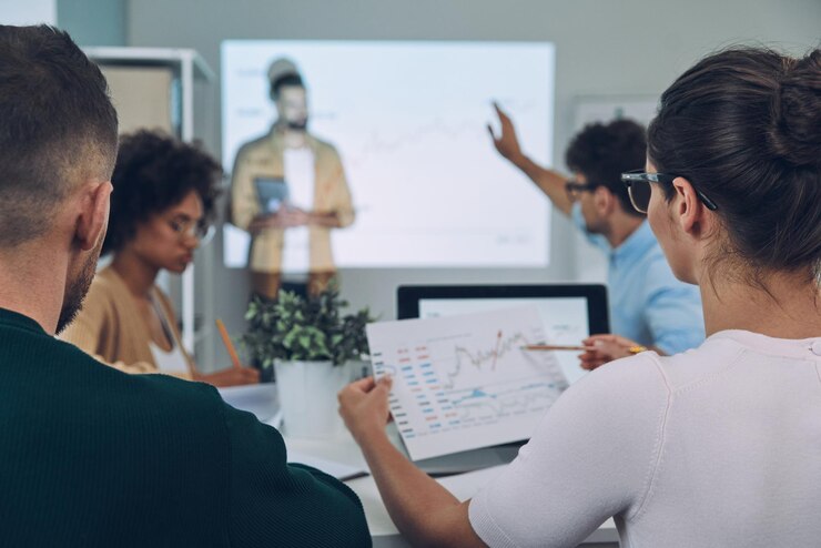 Foto grupo de jovens modernos em roupas casuais inteligentes analisando dados na tela de projeção no escritório