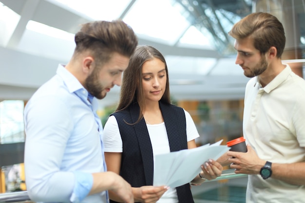 Grupo de jovens modernos em smart casual wear, tendo uma reunião de brainstorm em pé no escritório criativo.