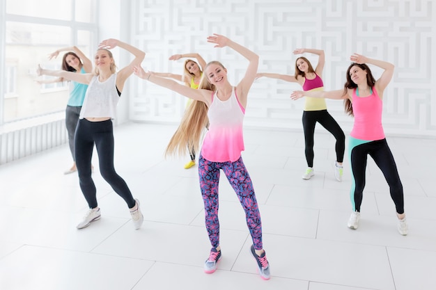 Grupo de jovens mulheres posando com os braços levantados enquanto fazia uma aula de dança de fitness