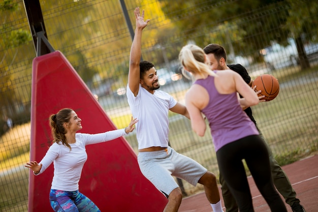 Grupo de jovens multirraciais jogando basquete ao ar livre