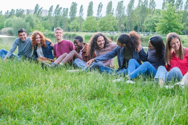 Grupo de jovens se divertindo à tarde no parque sentado na grama