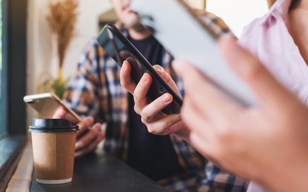 Grupo de jovens segurando e usando seus telefones celulares enquanto estão sentados juntos