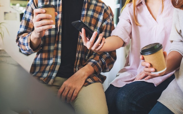 Foto grupo de jovens segurando e usando seus telefones celulares enquanto estão sentados juntos