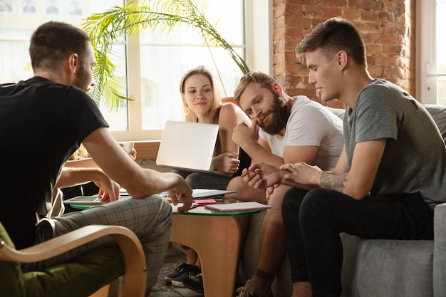 Grupo de jovens trabalhadores de escritório caucasianos se reunindo para discutir novas idéias. reunião criativa. trabalho em equipe e brainstorming. homens e mulheres se reúnem no cargo para planejar seu trabalho futuro. conceito de negócios.