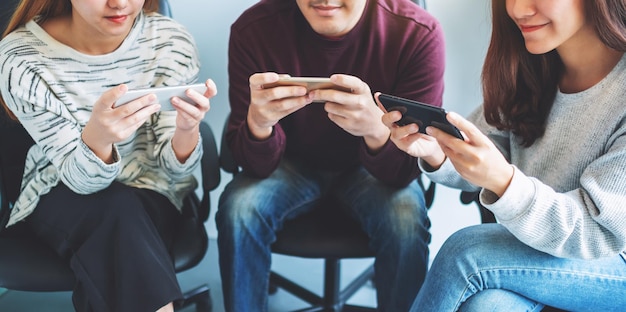 Grupo de jovens usando e jogando jogos no celular sentados juntos