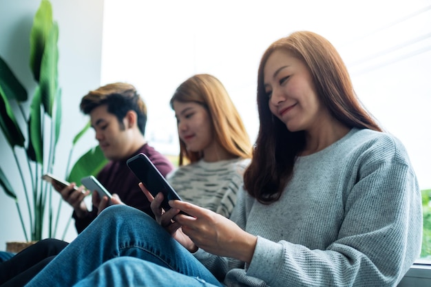 Grupo de jovens usando e olhando para o celular enquanto estão sentados juntos