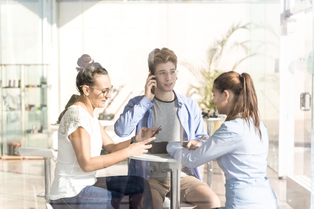 Grupo de jovens usando seu telefone celular em um coworking