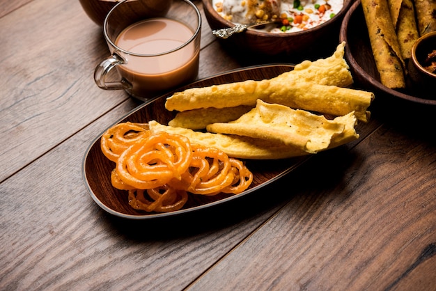 Grupo de lanches guzerate como jalebi-fafda, thepla, khaman dhokla, aloo bhujiya, khandvi, khakra, dahi vada, gathiya com chá quente