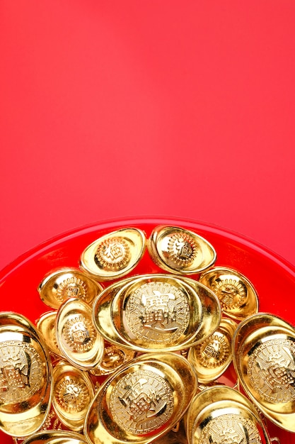 grupo de lingotes de ouro na bandeja vermelha no fundo vermelho. Língua chinesa no lingote significa riqueza