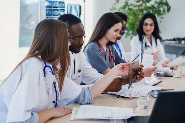 Grupo de médicos está estudando a história do paciente com doença. equipe de jovens médicos multiétnicas, tendo uma reunião na sala de conferências no hospital moderno e brilhante.