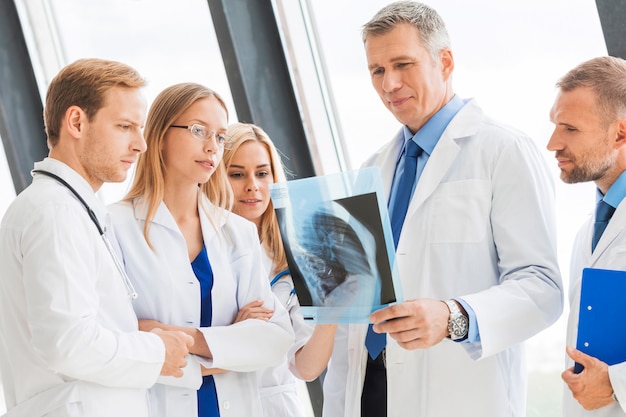 Grupo de médicos examina e discute raio-x em uma clínica ou hospital