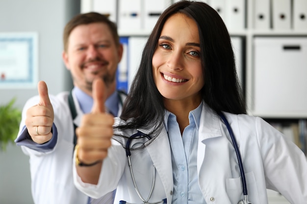 Grupo de médicos felizes sorrindo, mostrando o dedo no símbolo