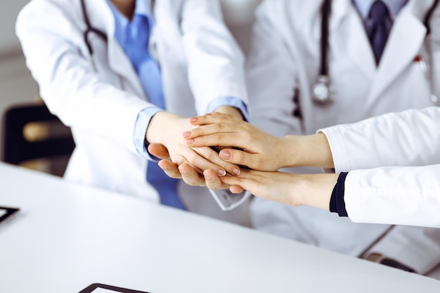 Grupo de médicos modernos juntando as mãos como um círculo e prontos para ajudar os pacientes. Trabalho em equipe em medicina durante a pandemia de Coronavirus. Covid 2019.