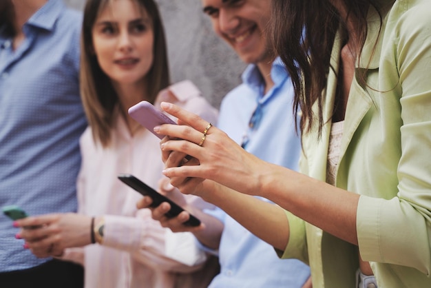 Grupo de melhores amigos de homens e mulheres assistindo conteúdo na rede social em seu dispositivo moderno de telefone