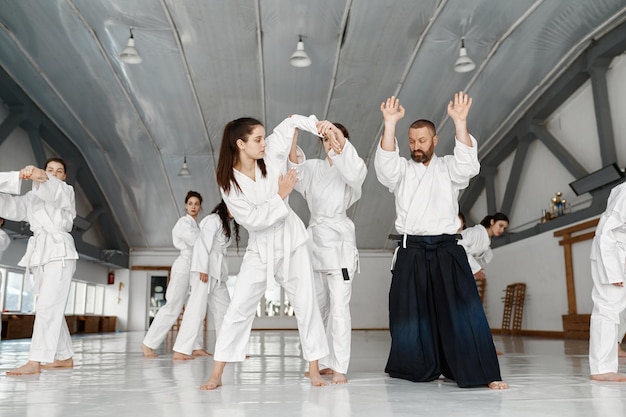 Grupo de meninas adolescentes tendo luta de aikido sob o controle do instrutor