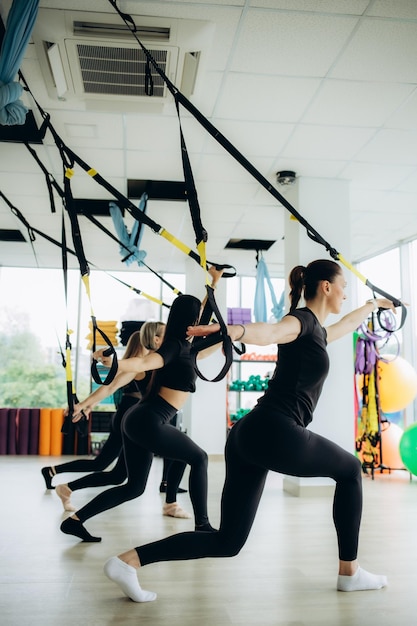 Grupo de meninas esportivas ativas em roupas esportivas pretas estão envolvidas em aptidão budgie na academia Bungee jumping na academia foto de alta qualidade