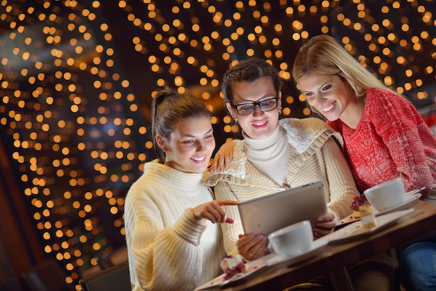 grupo de meninas felizes olhando para um tablet pc em um interior de casa e se divertir