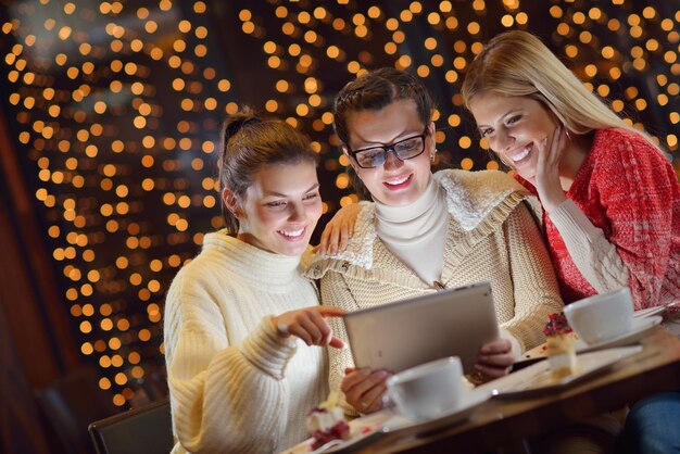 grupo de meninas felizes olhando para um tablet pc em um interior de casa e se divertir