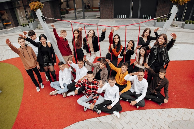 Foto grupo de muitos adolescentes felizes vestidos com roupas casuais se divertindo e se divertindo perto da faculdade conceito de amizade momentos de felicidade amizade escolar