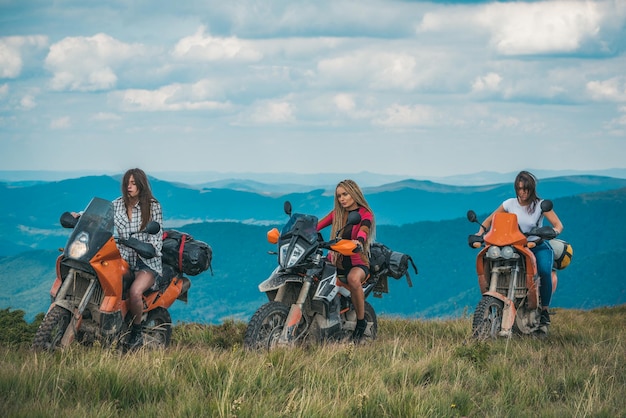 Foto grupo de mulher sexy na motocicleta mulher piloto garota ativa andando de moto no conceito de montanhas de aventura de passeio de motociclistas amigas de corrida na bicicleta esportes radicais na motocicleta