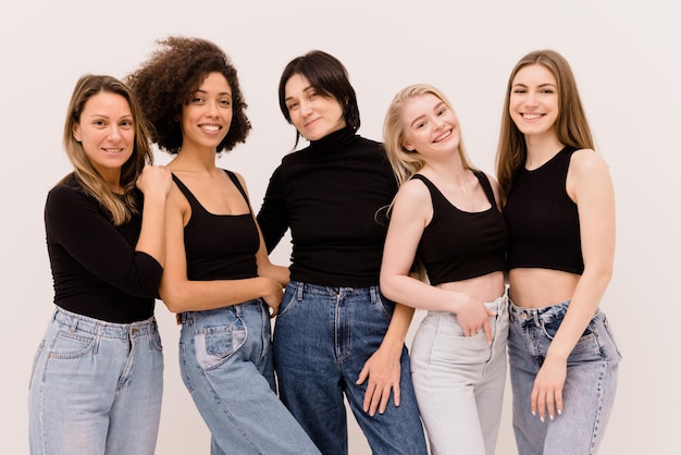 Grupo de mulheres africanas caucasianas adultas jovens felizes em roupas básicas, olhando para a câmera no fundo branco