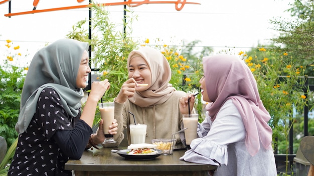 Grupo de mulheres asiáticas hijab sorrindo em um café com uma amiga