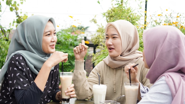 Grupo de mulheres asiáticas hijab sorrindo em um café com uma amiga