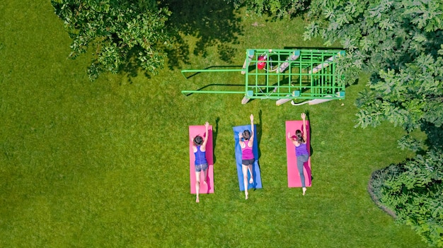 Grupo de mulheres ativas fazendo exercícios para mulheres fazendo exercícios no parque de esportes ao ar livre e fitness familiar