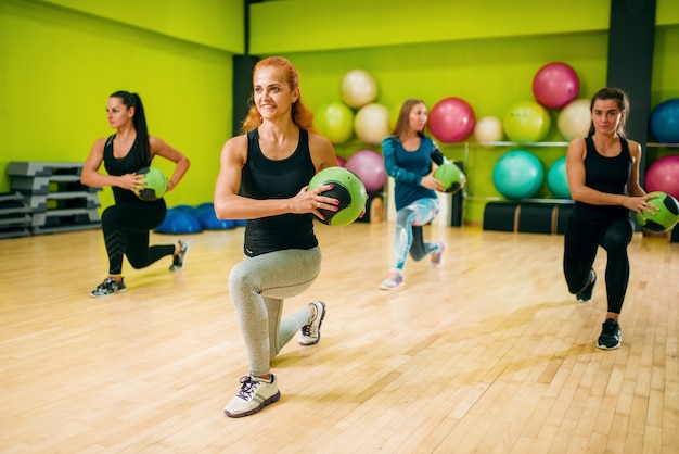 Grupo de mulheres com bolas em movimento, treino de fitness. trabalho em equipe do esporte feminino no ginásio. exercício físico, aeróbio