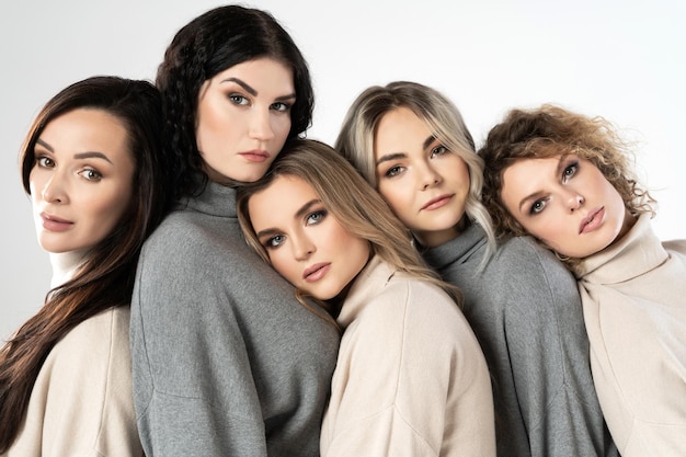 Grupo de mulheres diferentes vestindo jumpers de gola alta em fundo cinza Diversidade amizade e outros conceitos
