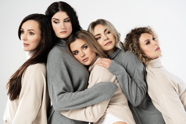 Grupo de mulheres diferentes vestindo jumpers de gola alta em fundo cinza Diversidade amizade e outros conceitos