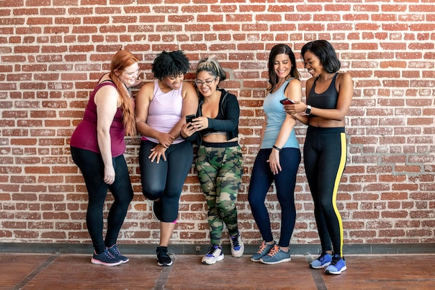 Grupo de mulheres esportivas em frente a uma parede de tijolos