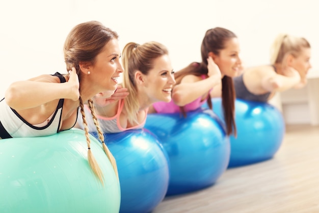 Grupo de mulheres felizes fazendo aeróbica com bolas em forma