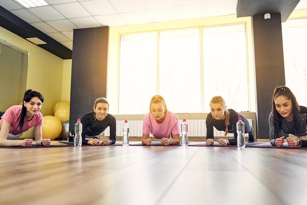 Grupo de mulheres jovens fazendo prancha juntas no ginásio